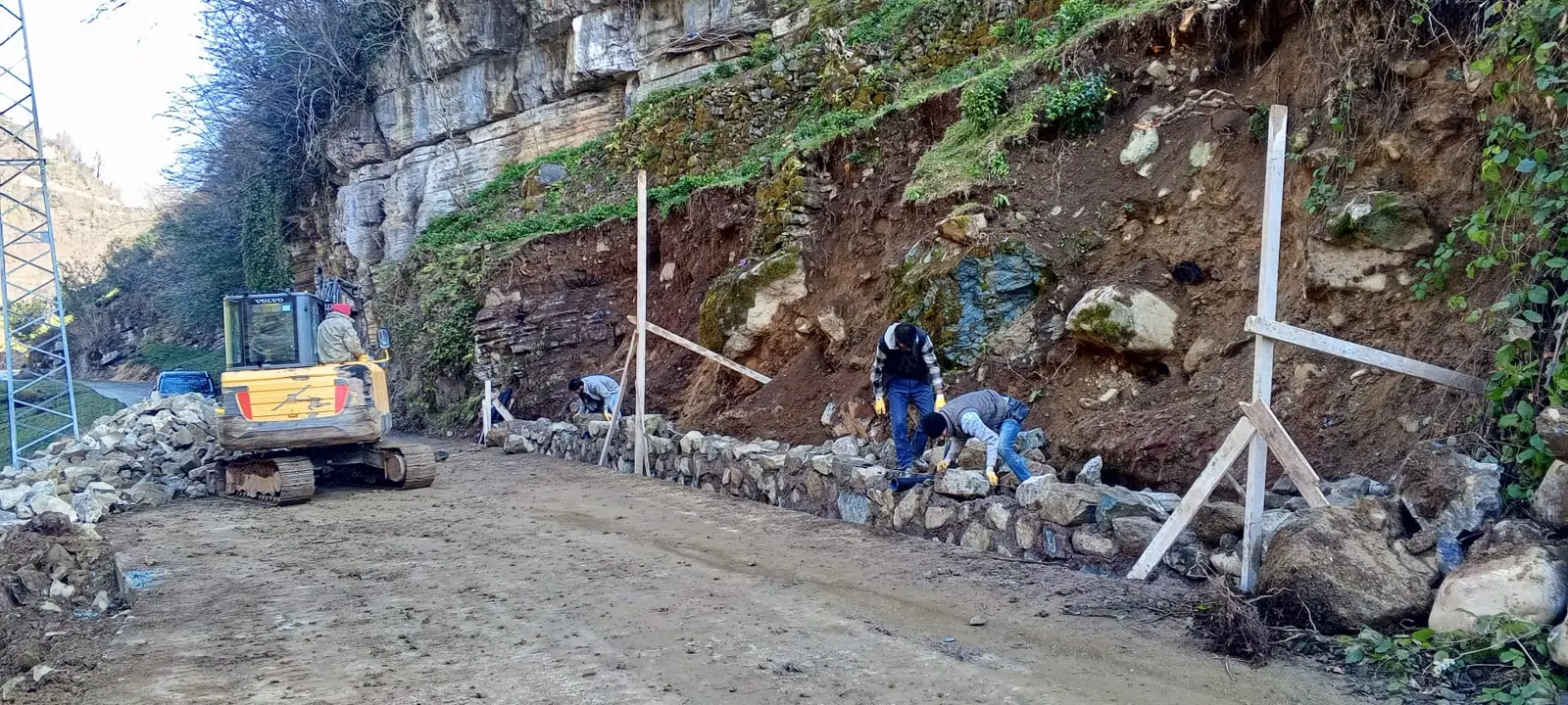Yol kenarında iş makinesiyle taş duvar yapımı